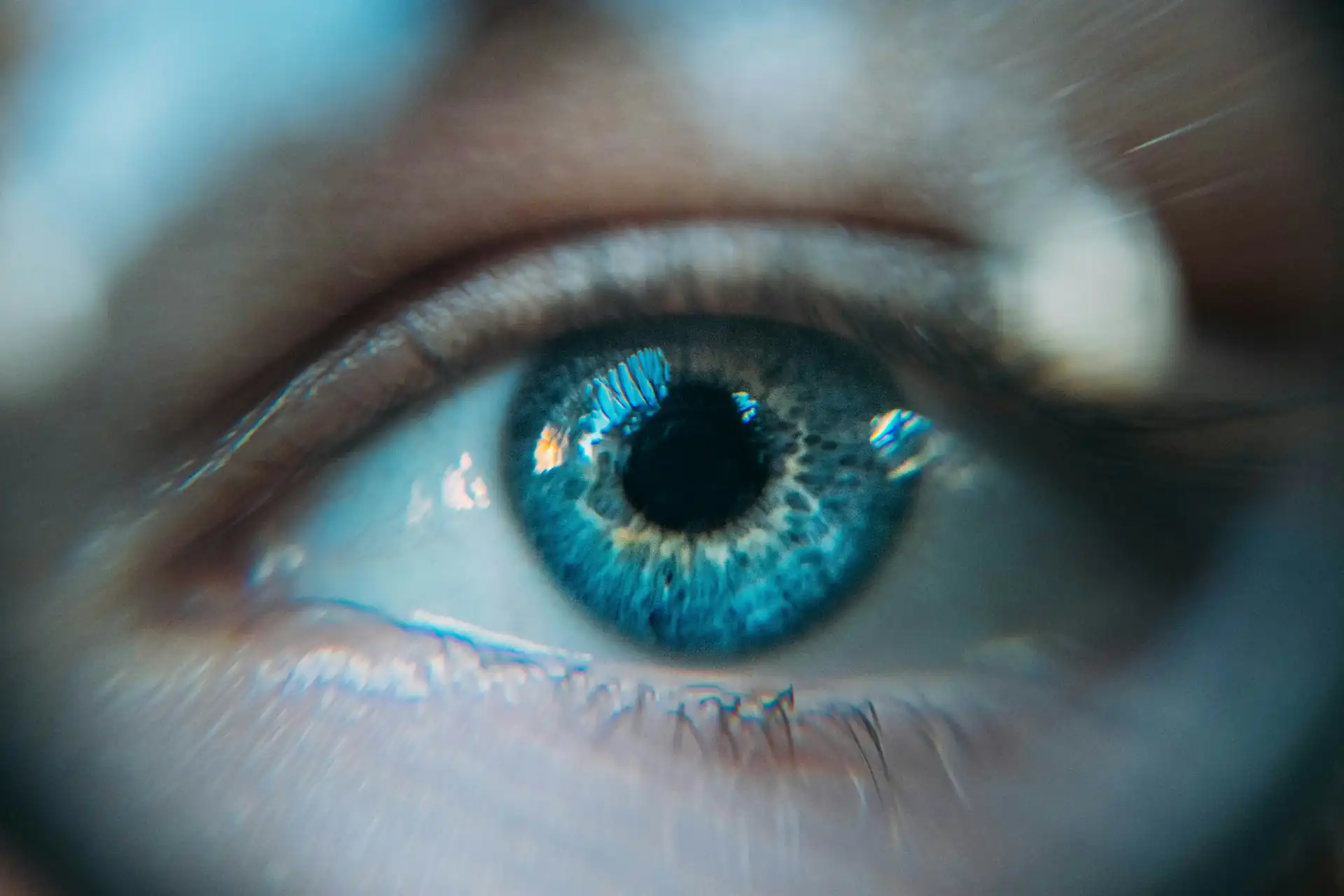 Primer plano de un ojo de iris azul con la luz reflejada en la córnea